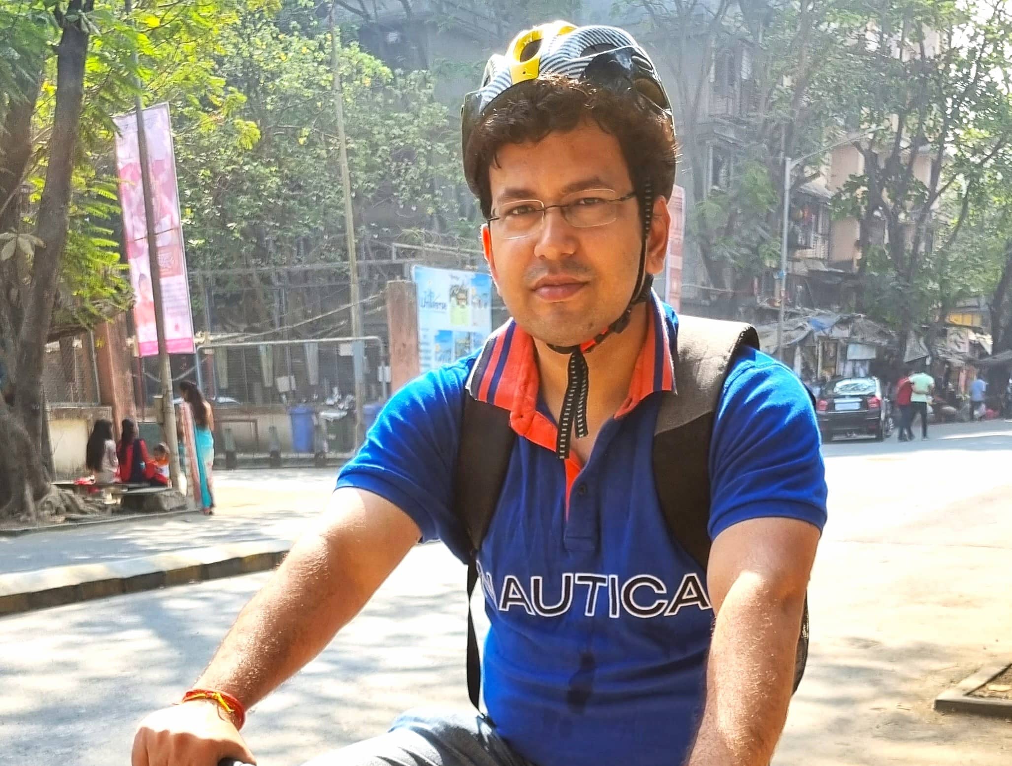 A man with black-yellow coloured helmet posing with a cycle